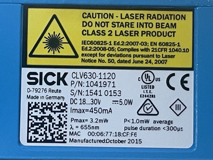 Close-up of a blue laser enclosure with a white and yellow product label. The label shows the brand SICK, model CLV630-1120, class 2 laser product warning, technical specifications, a QR code, and certification marks including UL and CE.