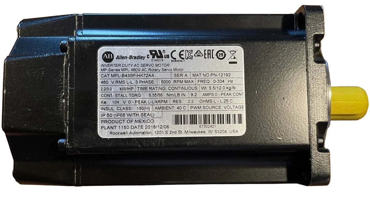 An Allen-Bradley industrial servo motor, model MFR 480V AC Servo Motor, shown from a top-down angle on a wooden surface. The motor has a black plastic housing with a white technical specification label in the center and a yellow shaft visible on the right.