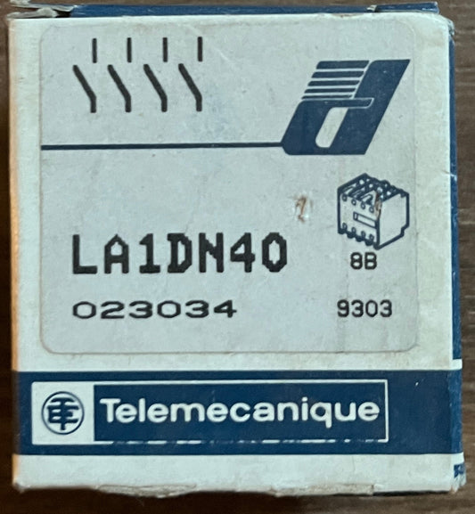A small Telemecanique product box labeled LA1DN40, placed on a brown wooden surface.