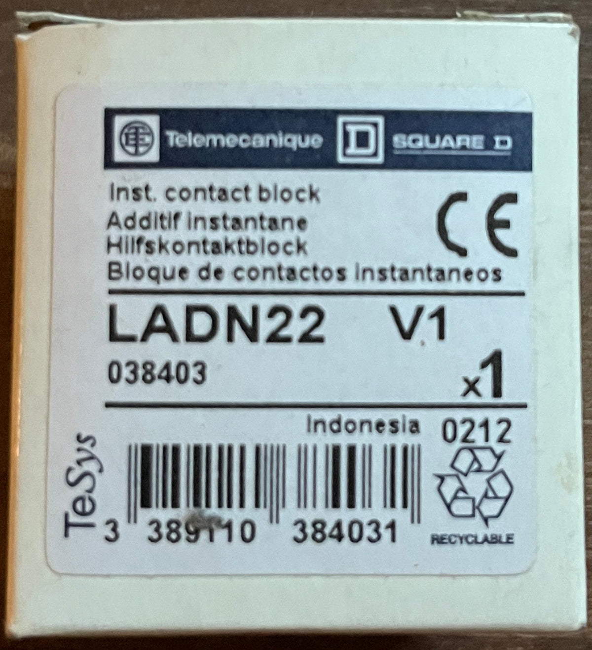 A small white Telemecanique LADN22 V1 instant contact block box on a dark brown wooden surface.