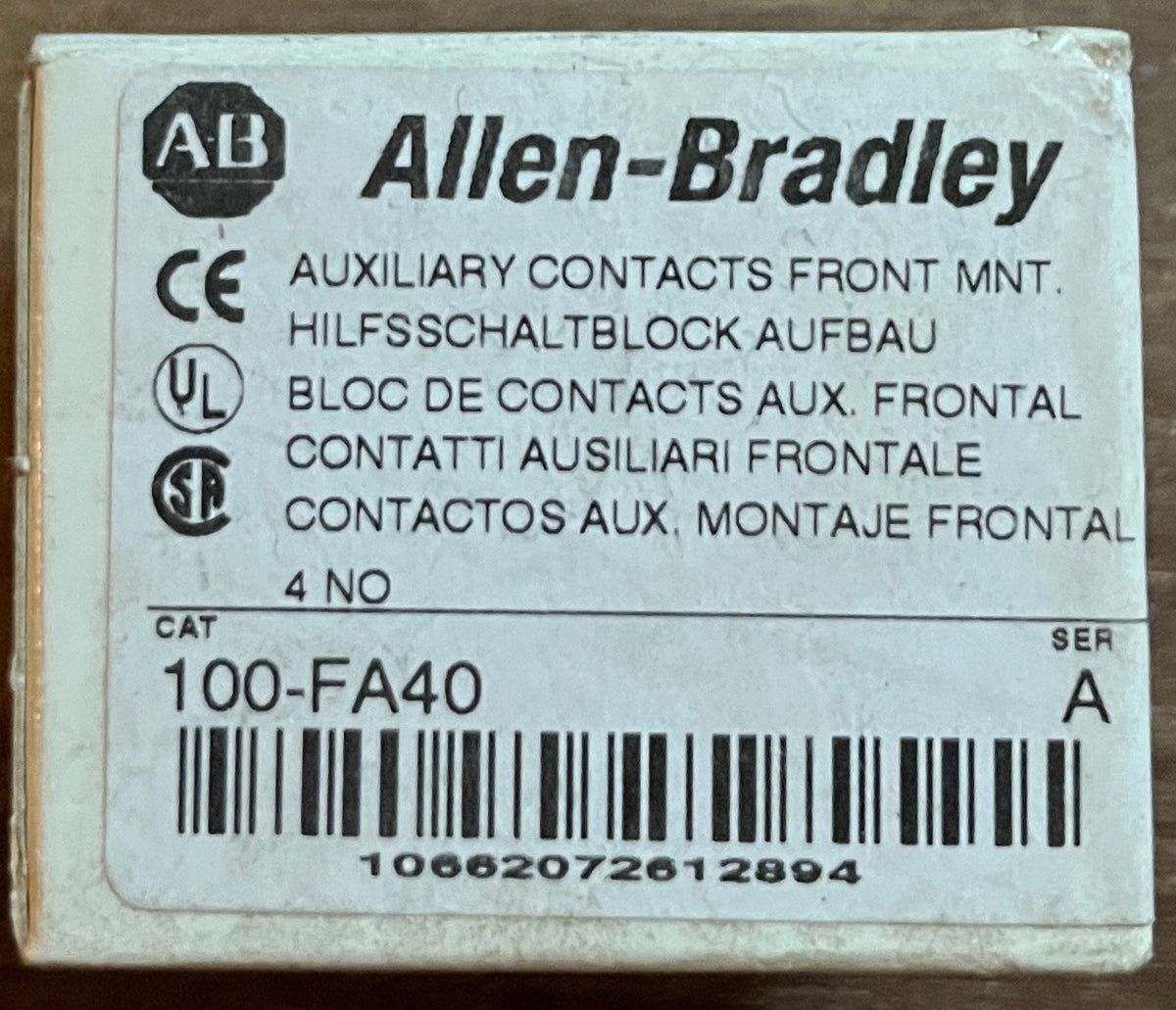 A small Allen-Bradley electrical component box labeled '100-FA40' with a barcode, placed on a brown wooden surface.