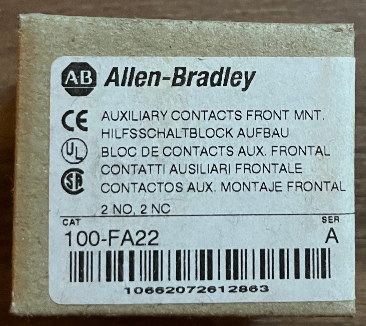 A small Allen-Bradley product box with a white label and barcode, placed on a brown wooden surface.